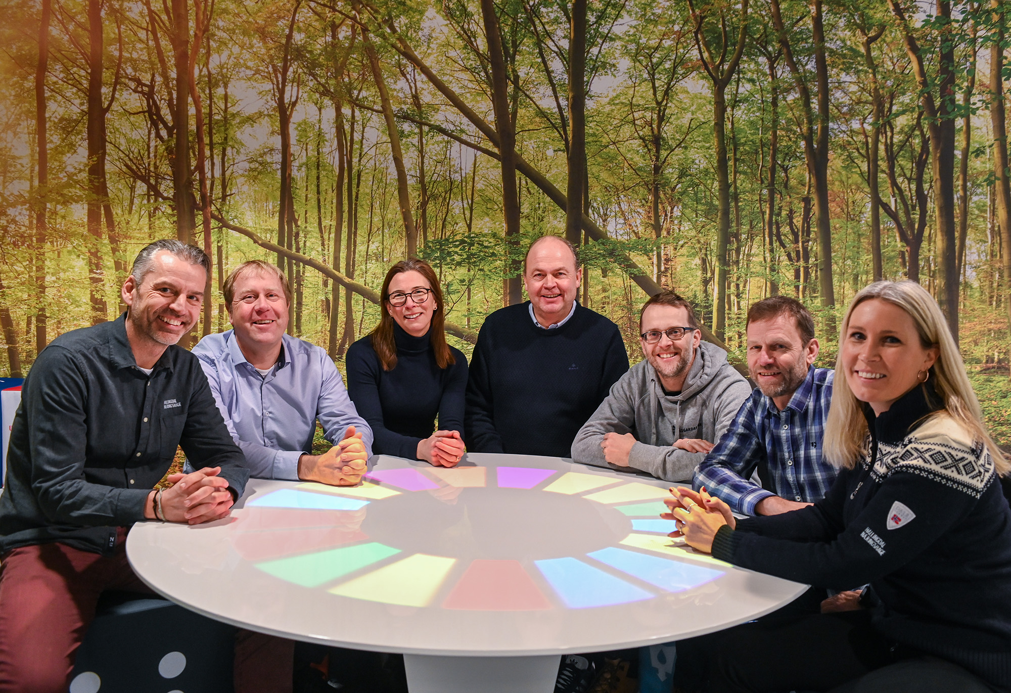 7 personer fra Sparebankstiftelsen Hallingdal, Bærekraft Hallingdal og klimakoordinator for kommunene samlet rundt bord med bilde av natur i bakgrunnen.